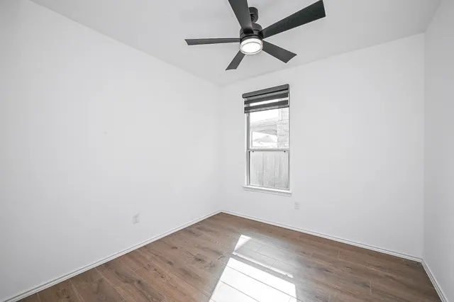 an empty room with a window and a fan