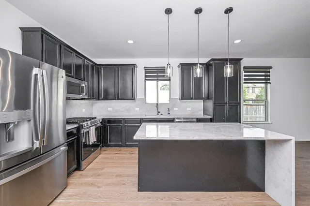 a kitchen with stainless steel appliances granite countertop a sink a stove and a refrigerator