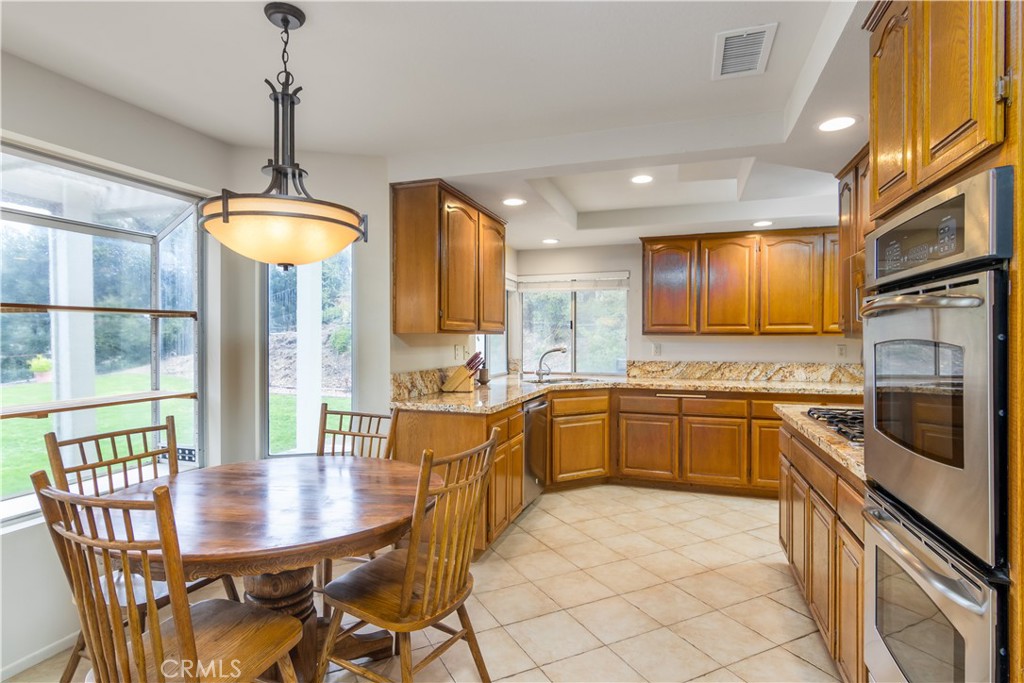 2887 Queens Way Thousand Oaks, CA 91362 - Photo 14 of 35 a kitchen with stainless steel appliances granite countertop a stove a sink a microwave a dining table and chairs