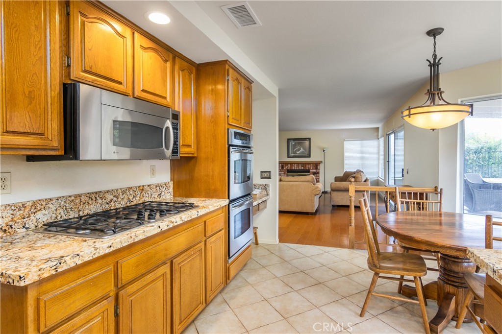 2887 Queens Way Thousand Oaks, CA 91362 - Photo 16 of 35 a kitchen with stainless steel appliances kitchen island granite countertop a stove a sink a dining table and chairs with wooden floor