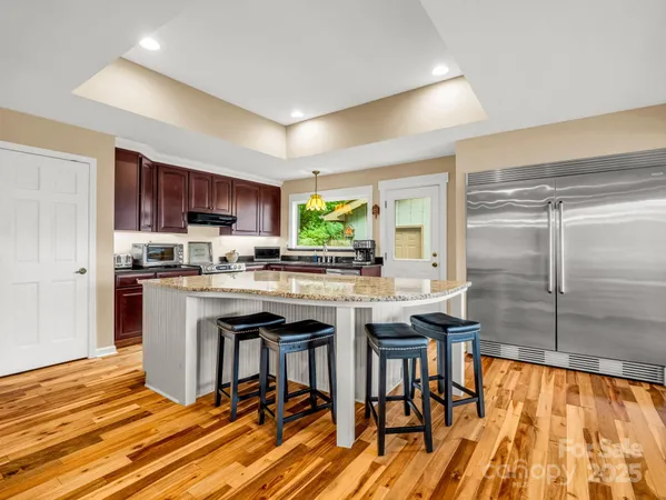 a kitchen with stainless steel appliances granite countertop a stove top oven a sink dishwasher a dining table and chairs with wooden floor