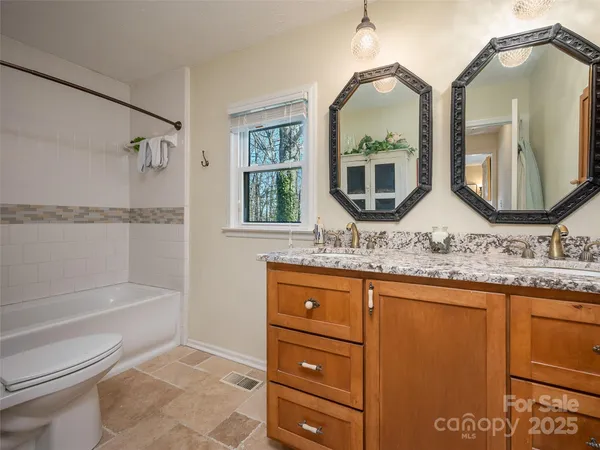 a bathroom with a granite countertop sink mirror toilet and bathtub