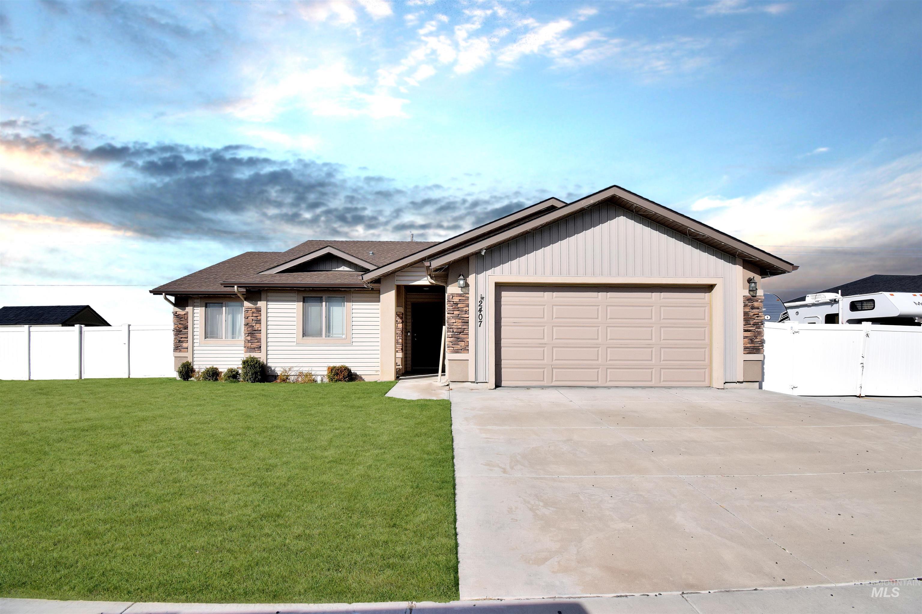 2407 Forge Street Twin Falls, ID 83301 - Photo 1 of 20 Ranch-style home featuring concrete driveway, stone siding, an attached garage, a gate, and a shingled roof
