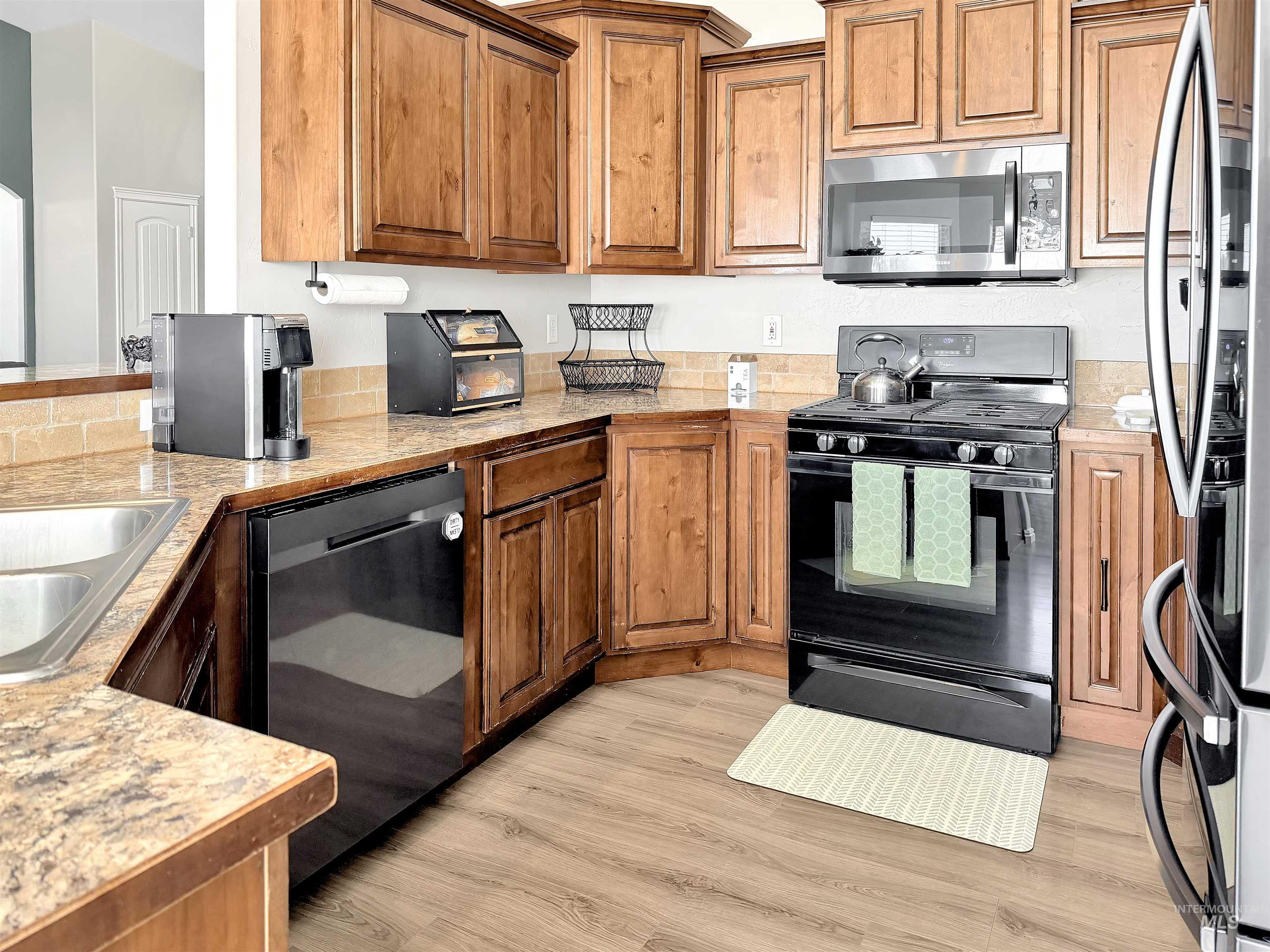 2407 Forge Street Twin Falls, ID 83301 - Photo 7 of 20 Kitchen with black appliances, light countertops, wood finish cabinetry, and light wood finished floors