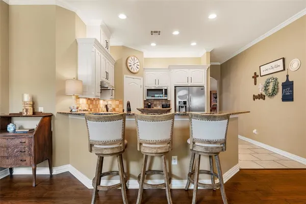 a kitchen with stainless steel appliances kitchen island granite countertop a table chairs and a refrigerator