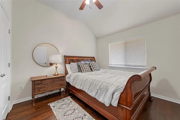 a bedroom with a bed a dresser and a potted plant