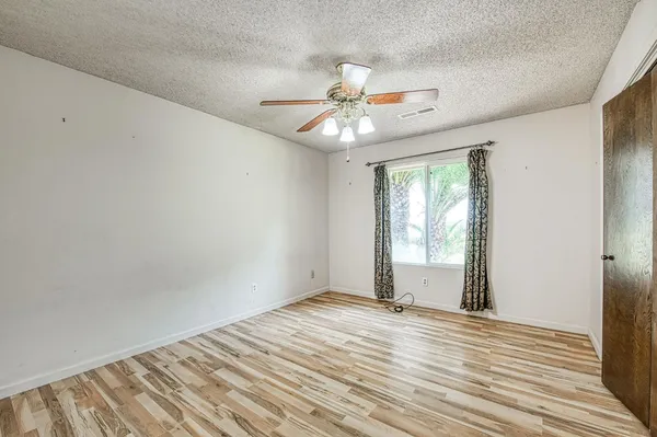 an empty room with wooden floor fan and windows