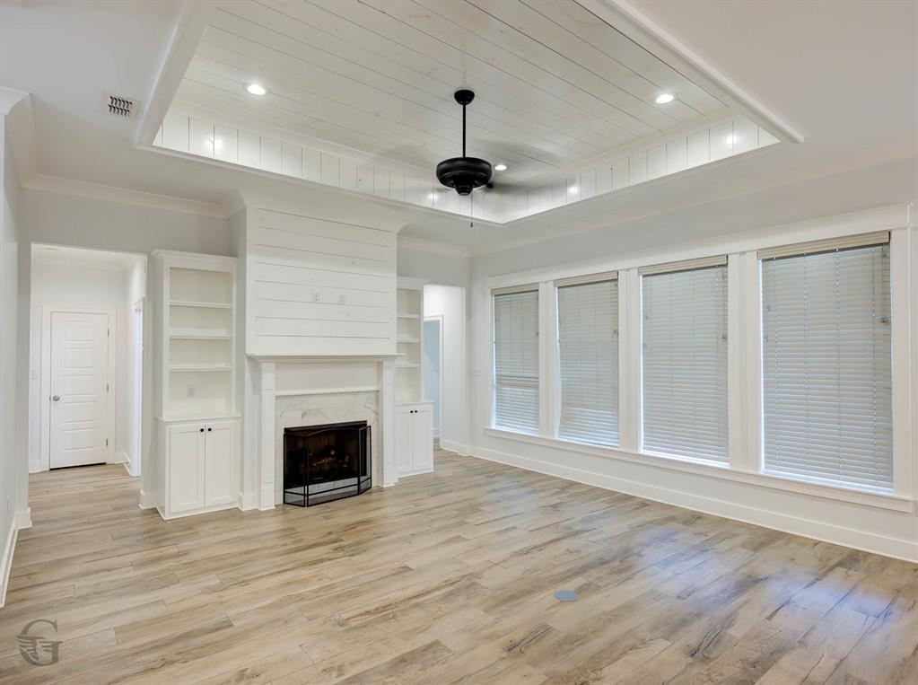 605 Meridian Way Benton, LA 71006 - Photo 5 of 29 Spacious room featuring wood-finish flooring, a tray ceiling with recessed lighting and a ceiling fan, a fireplace with a mantel and hearth, and built-in shelving with cabinetry