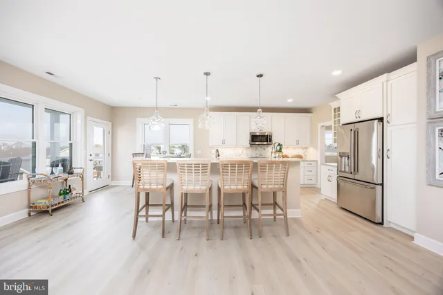 a dining room with stainless steel appliances a dining table chairs refrigerator and sink