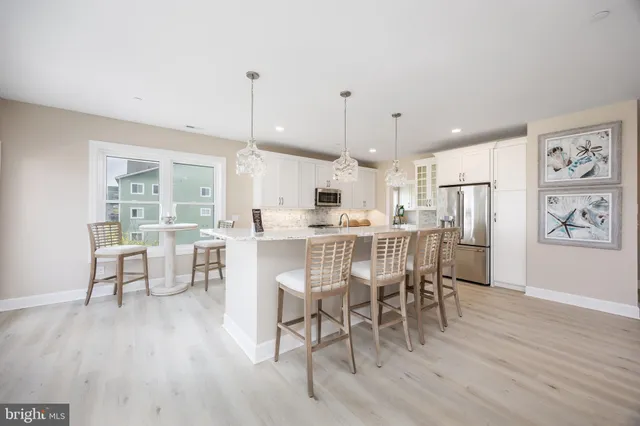 a dining room with stainless steel appliances a wooden table chairs and view living room