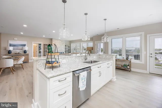 a large kitchen with kitchen island a large counter top a sink appliances and cabinets