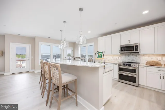 a kitchen with stainless steel appliances kitchen island granite countertop a stove top oven a sink with island and chairs in it