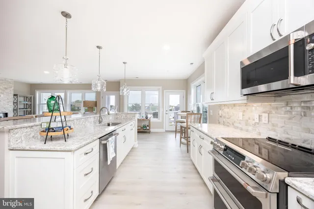 a large kitchen with stainless steel appliances kitchen island granite countertop a sink and cabinets