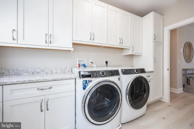 a utility room with granite countertop white cabinets and washer