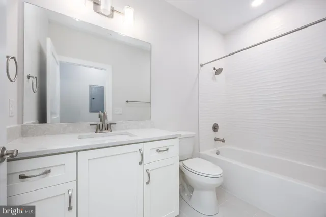 a bathroom with a granite countertop toilet a sink and a bathtub