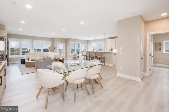 a living room with stainless steel appliances furniture a dining table and kitchen view
