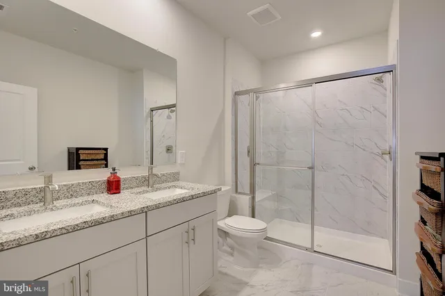 a bathroom with a granite countertop sink a toilet and shower
