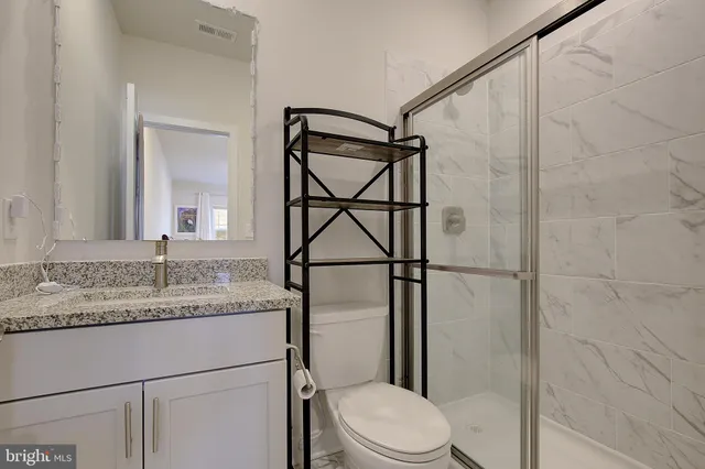 a bathroom with a granite countertop sink toilet and a mirror