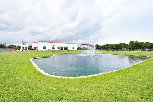 a view of a white house with a big yard and large trees