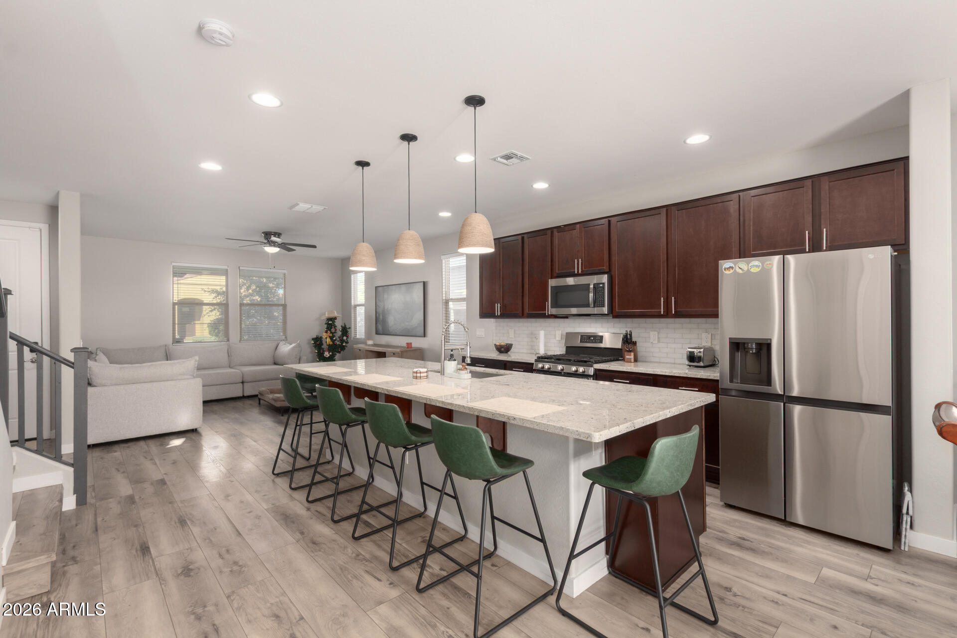 21073 West Berkeley Road Buckeye, AZ 85396 - Photo 13 of 41 a kitchen with stainless steel appliances a refrigerator a stove a sink a dining table and chairs with wooden floor