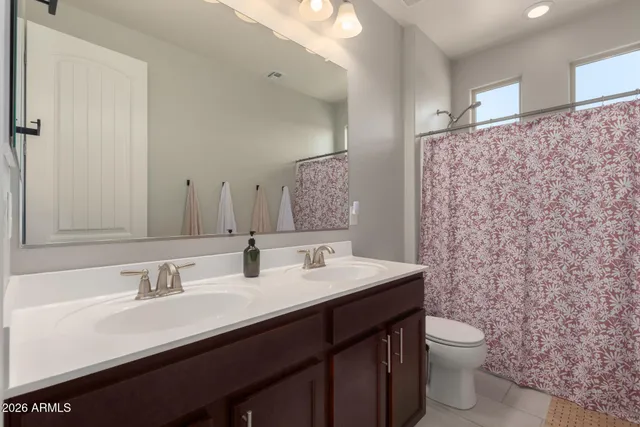 a bathroom with a double vanity sink toilet and a mirror