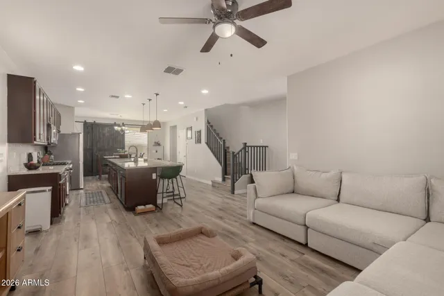 a living room with furniture kitchen view and a wooden floor