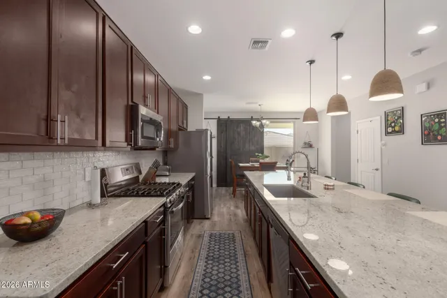 a kitchen with stainless steel appliances granite countertop a sink a stove and a wooden floors