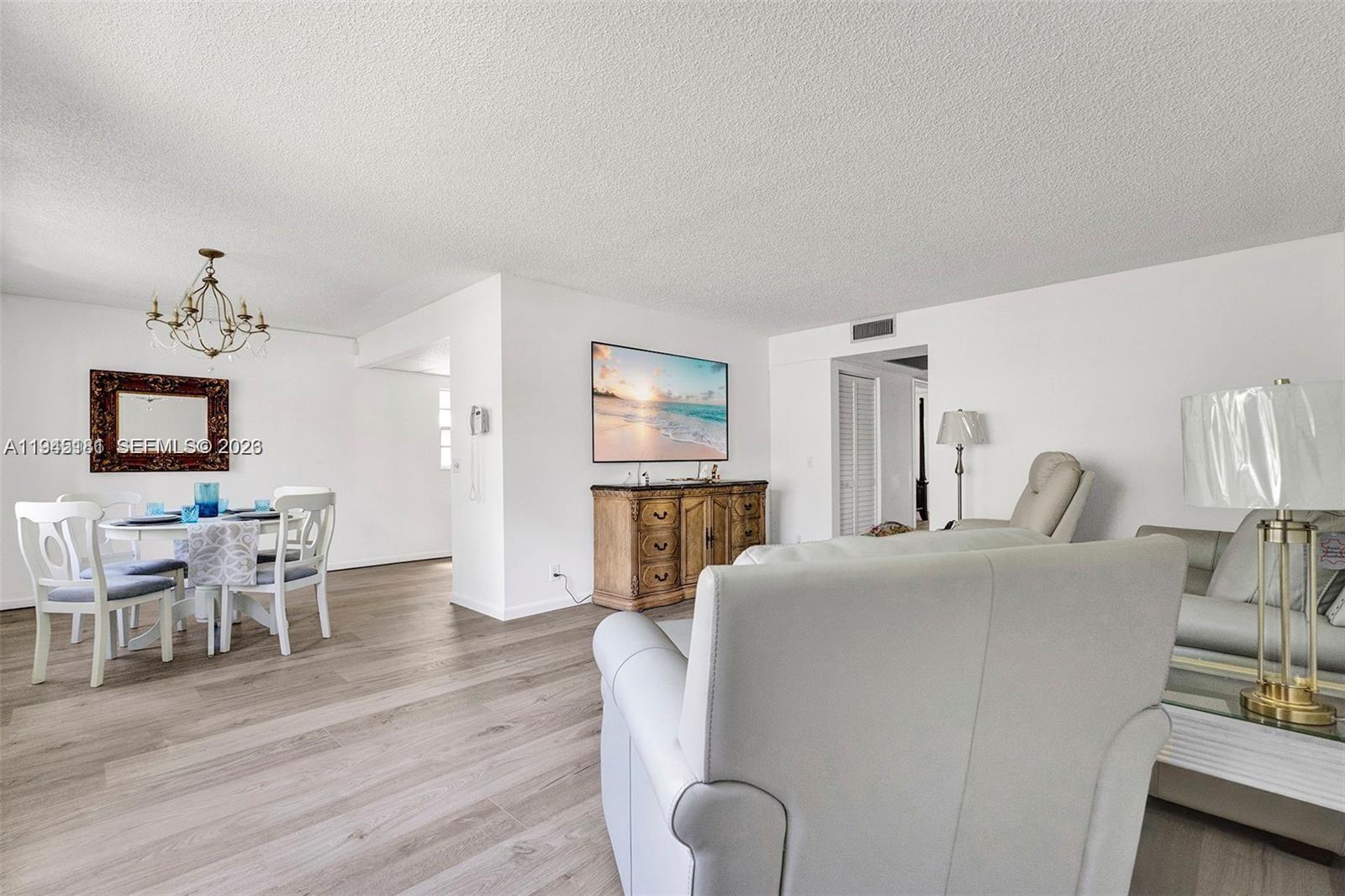 400 Southwest 134th Way, Unit 201F Pembroke Pines, FL 33027 - Photo 11 of 28 a living room with furniture a dining table and a flat screen tv