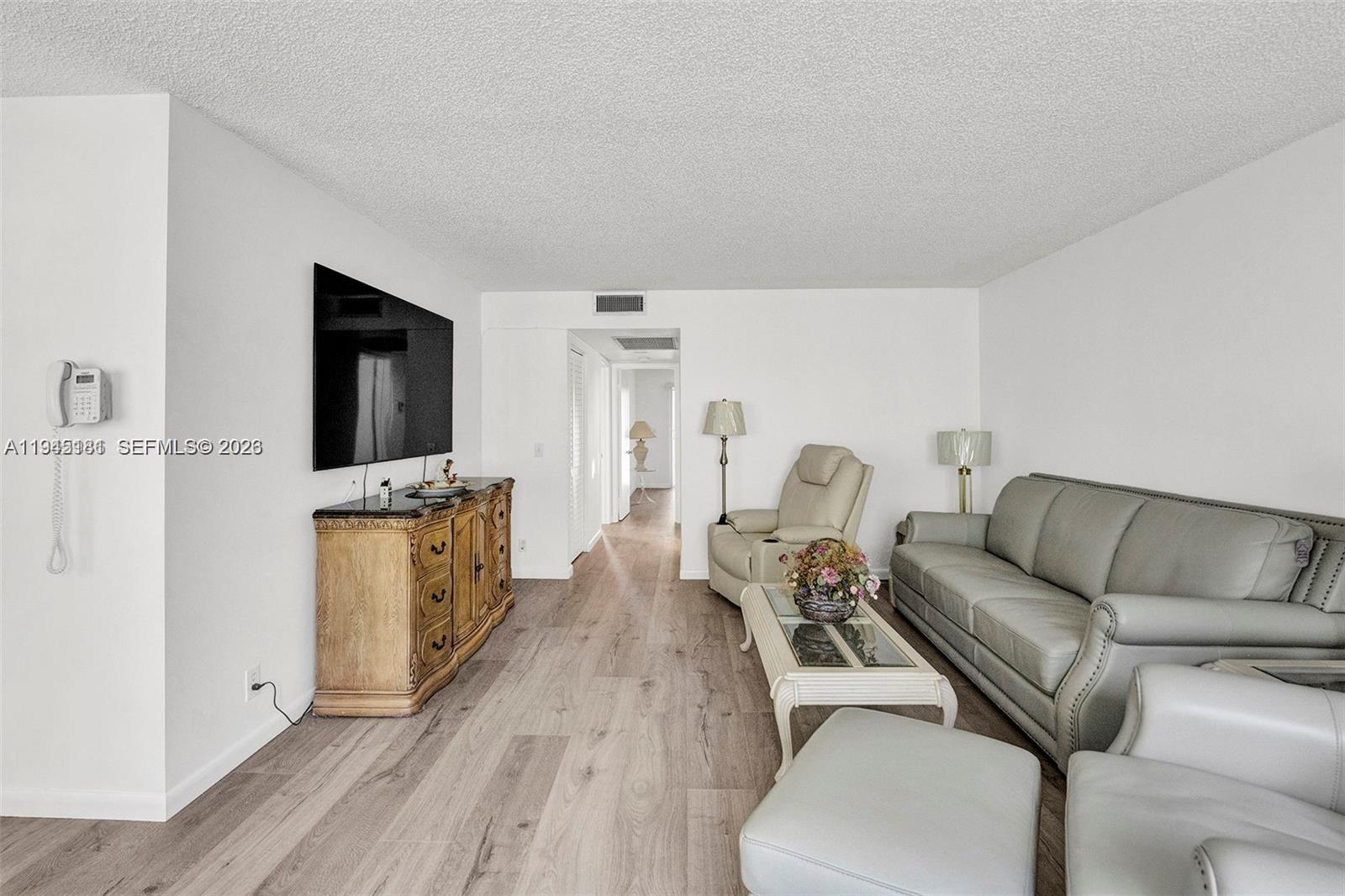 400 Southwest 134th Way, Unit 201F Pembroke Pines, FL 33027 - Photo 12 of 28 a living room with furniture a flat screen tv and a wooden floor