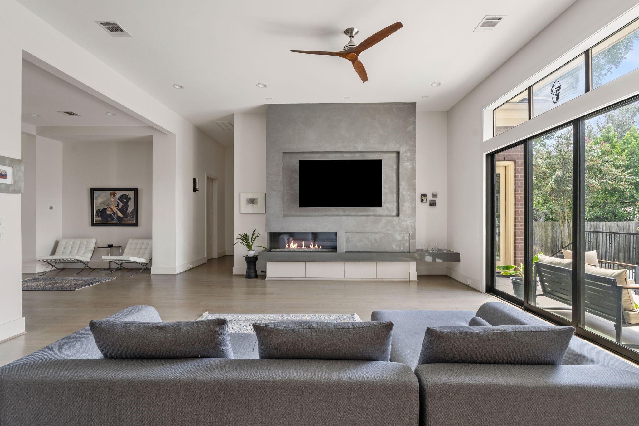 5427 Maple Street Houston, TX 77096 - Photo 2 of 46 The family room's focal point is a floor-to-ceiling accented fireplace wall with a built-in space for a mounted television above a linear gas fireplace, flanked by black-framed sliding doors to the back patio.
