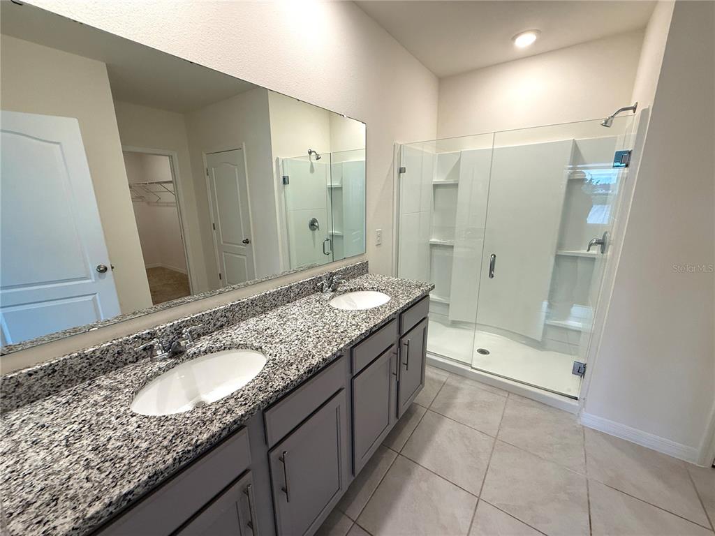2877 Sunridge Loop St. Cloud, FL 34771 - Photo 7 of 19 a bathroom with a granite countertop double vanity sink mirror double and shower