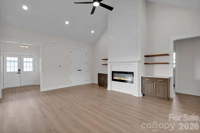an empty room with wooden floor fireplace and windows