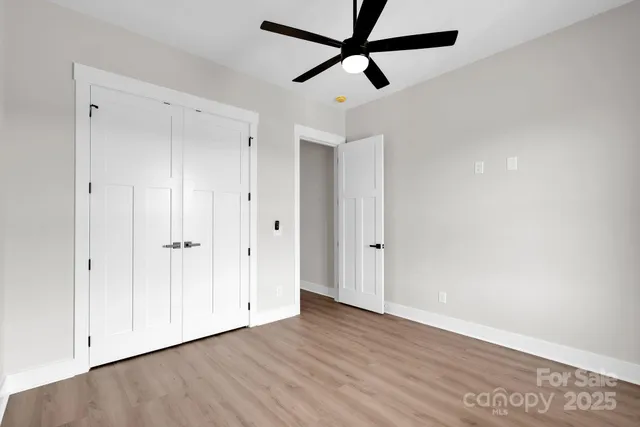 an empty room with wooden floor and ceiling fan