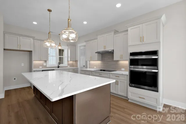 a large kitchen with kitchen island a stove a sink a center island and cabinets