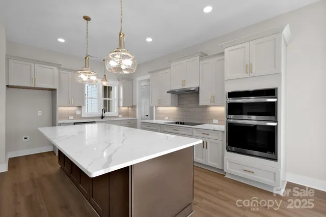 a kitchen with kitchen island a stove cabinets and wooden floor