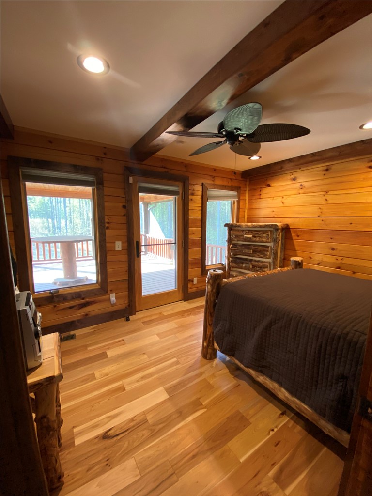 128 McAlister Road West Union, SC 29696 - Photo 25 of 40 Natural light floods this inviting bedroom, featuring warm wood paneling and direct deck access.