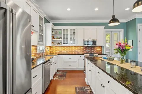 a kitchen with stainless steel appliances granite countertop a stove top oven a sink a dining table and chairs