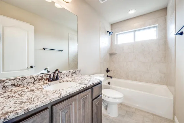 a bathroom with a granite countertop sink a toilet and bathtub