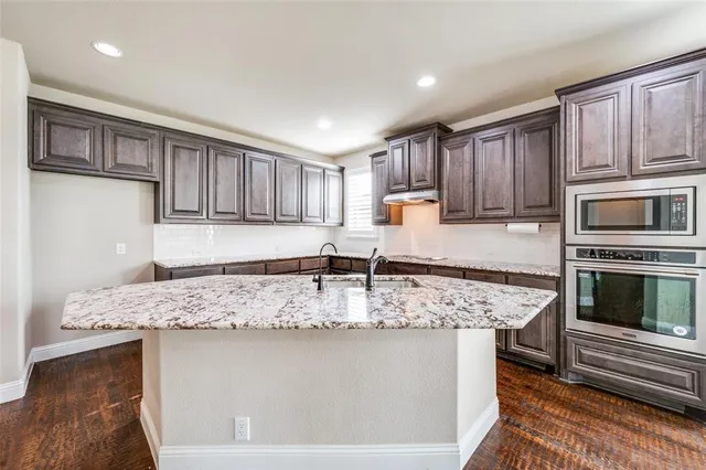 a kitchen with kitchen island granite countertop a stove sink and microwave
