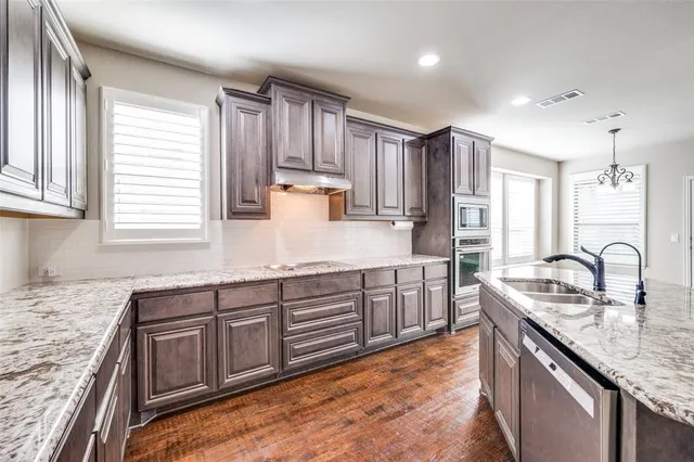 a kitchen with kitchen island granite countertop a sink stove and cabinets