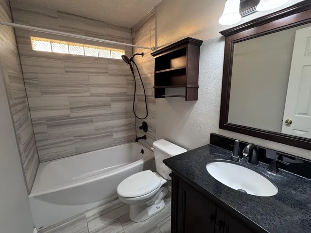 a bathroom with a granite countertop sink toilet and shower