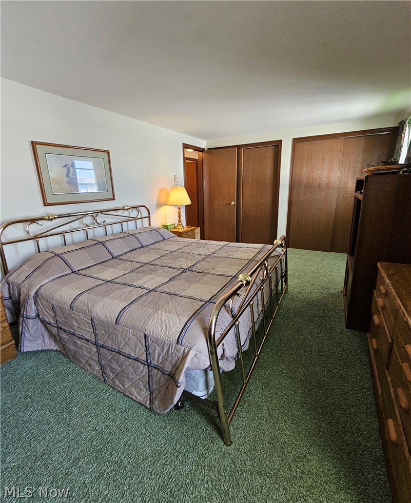 Bedroom with dark colored carpet and two closets