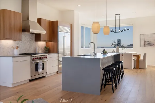 a kitchen with kitchen island granite countertop a stove a sink a dining table and chairs with wooden floor