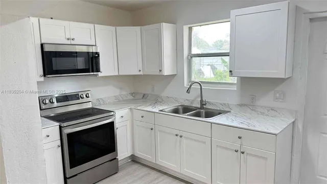 a kitchen with white cabinets stainless steel appliances and sink