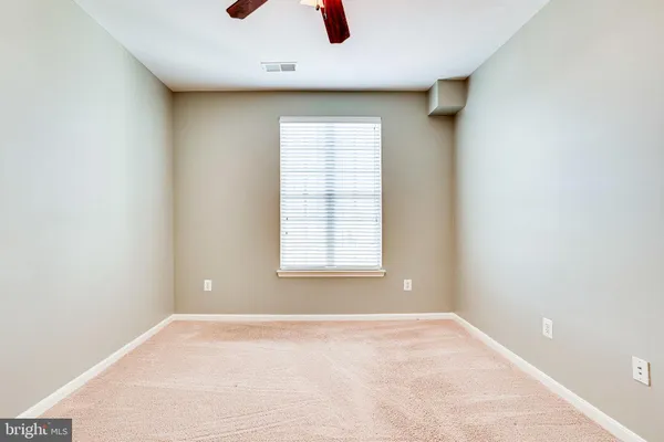 an empty room with a ceiling fan and carpet