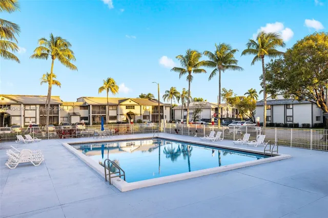 a view of a swimming pool with a lounge chair and palm trees