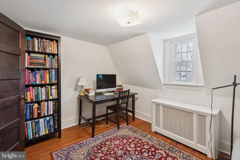 a view of a workspace with bookshelf and a window