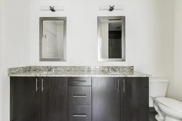 a bathroom with a granite countertop sink a toilet and mirror