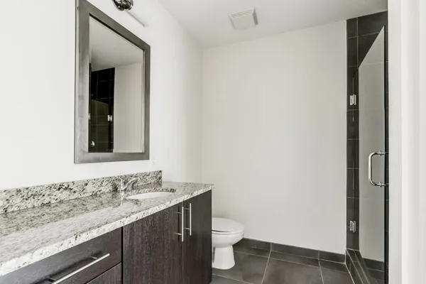 a bathroom with a granite countertop sink and a toilet