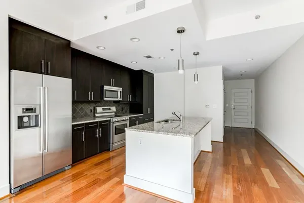 a large kitchen with stainless steel appliances a stove a refrigerator a sink and a oven
